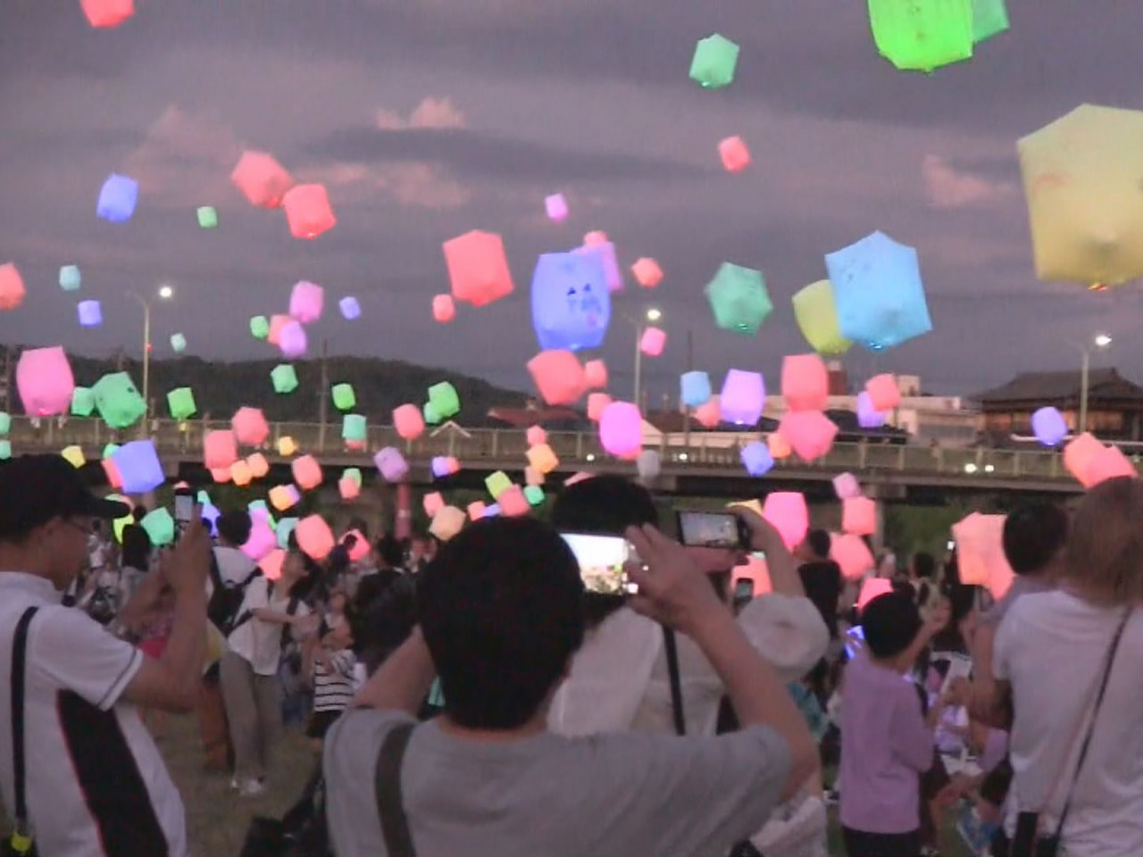 人工雪が舞い、花火がきらめく夏の夜空に色鮮やかなスカイランタンを浮かべるイベント...